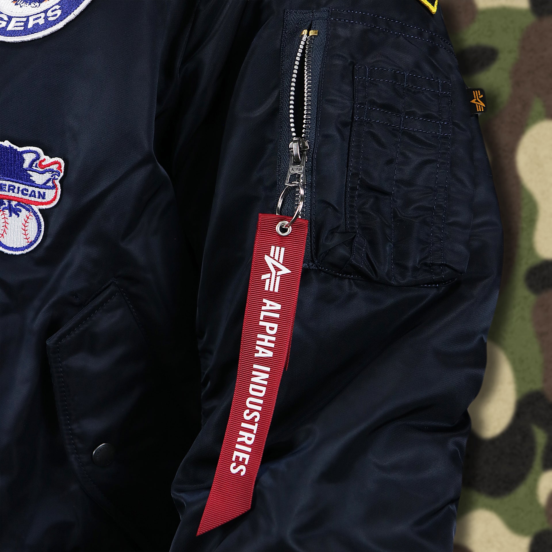 The Alpha Industries Hangtag on the Detroit Tigers MLB Patch Alpha Industries Reversible Bomber Jacket With Camo Liner | Navy Blue Bomber Jacket