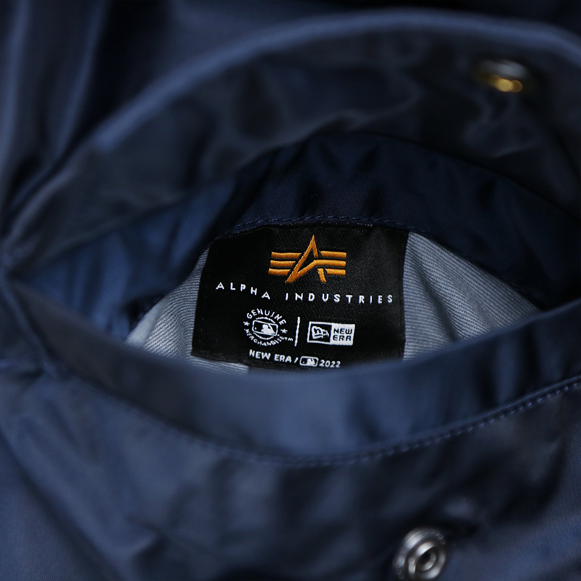 The Alpha Industries Tag on the Detroit Tigers MLB Patch Alpha Industries Reversible Bomber Jacket With Camo Liner | Navy Blue Bomber Jacket