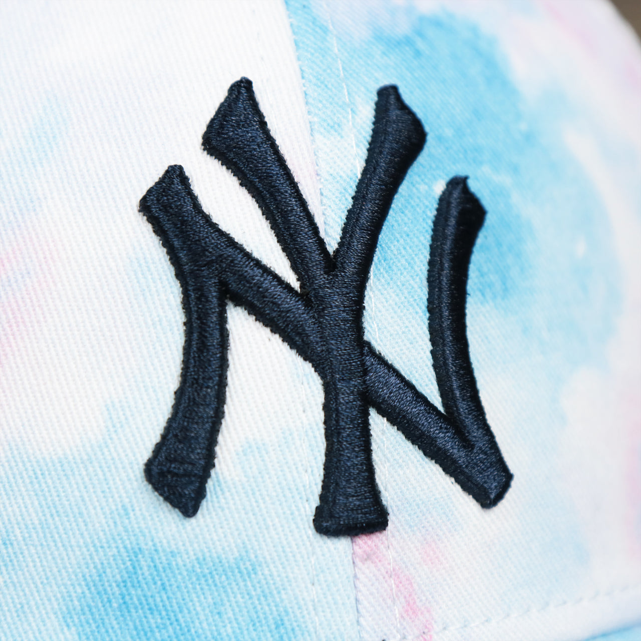The Yankees Logo on the Women’s New York Yankees Tie Dye Print Gray Bottom Mesh Trucker Hat | White Mesh Snapback