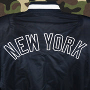 The New York Wordmark on the New York Yankees MLB Patch Alpha Industries Reversible Bomber Jacket With Camo Liner | Navy Blue Bomber Jacket