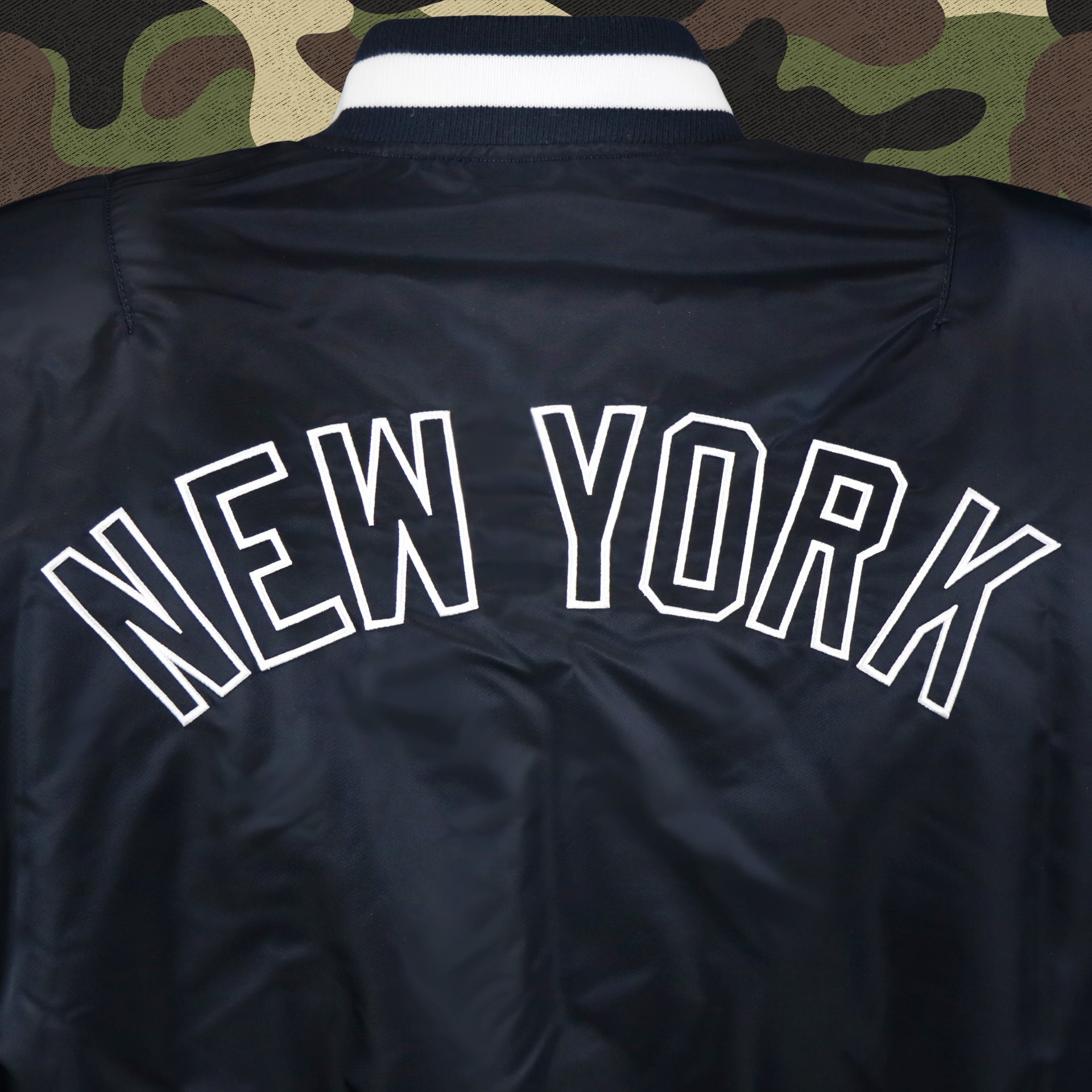 The New York Wordmark on the New York Yankees MLB Patch Alpha Industries Reversible Bomber Jacket With Camo Liner | Navy Blue Bomber Jacket