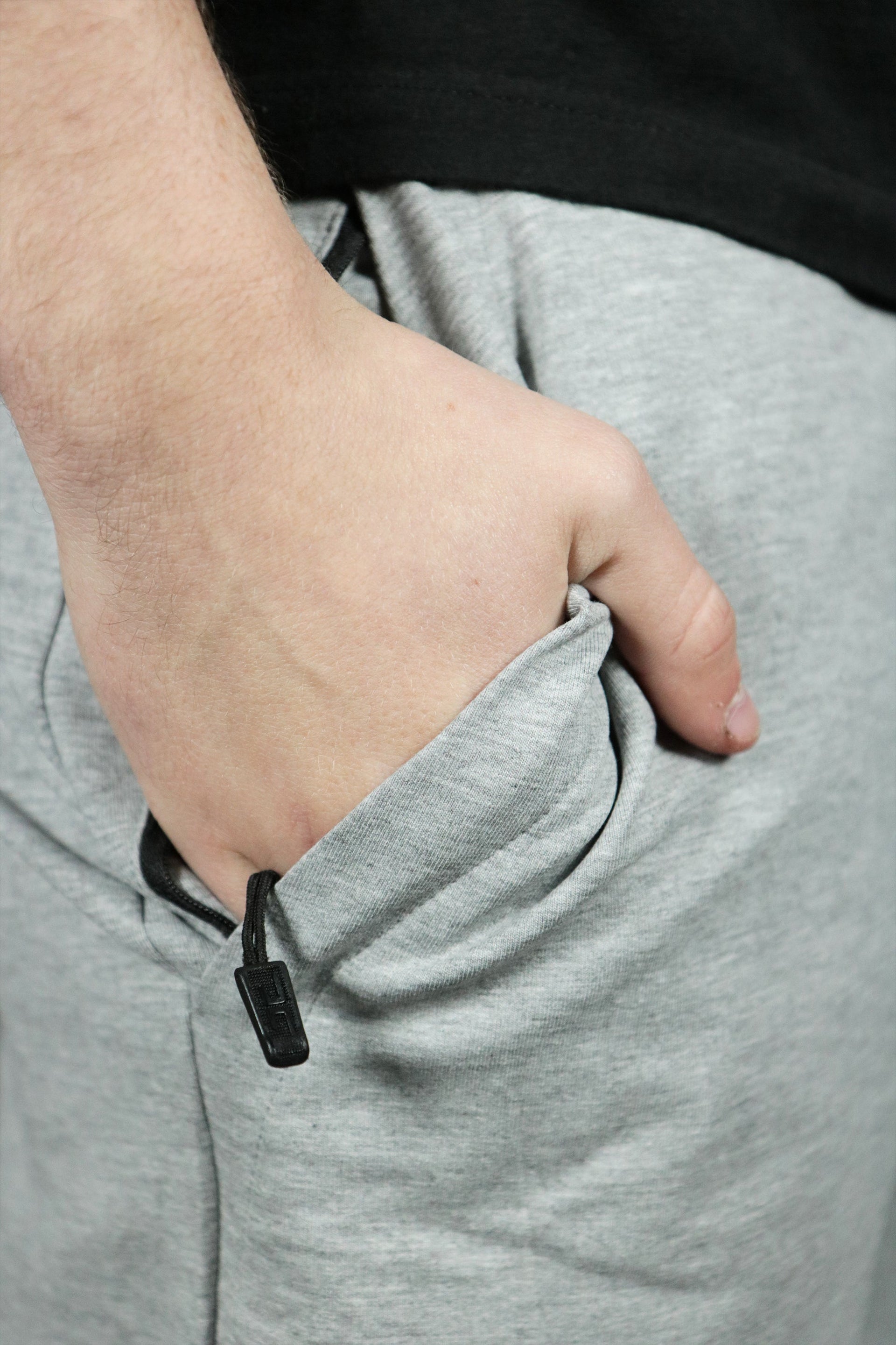 The zipped pocket of the heather grey toweling shorts.
