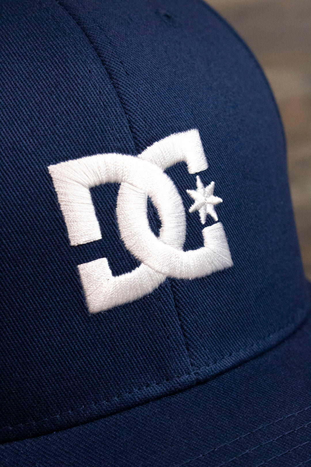 the logo on the Navy Blue Skater Hat | DC Shoes Blue Bottom Navy Flexfit Cap is made of white satin embroidery