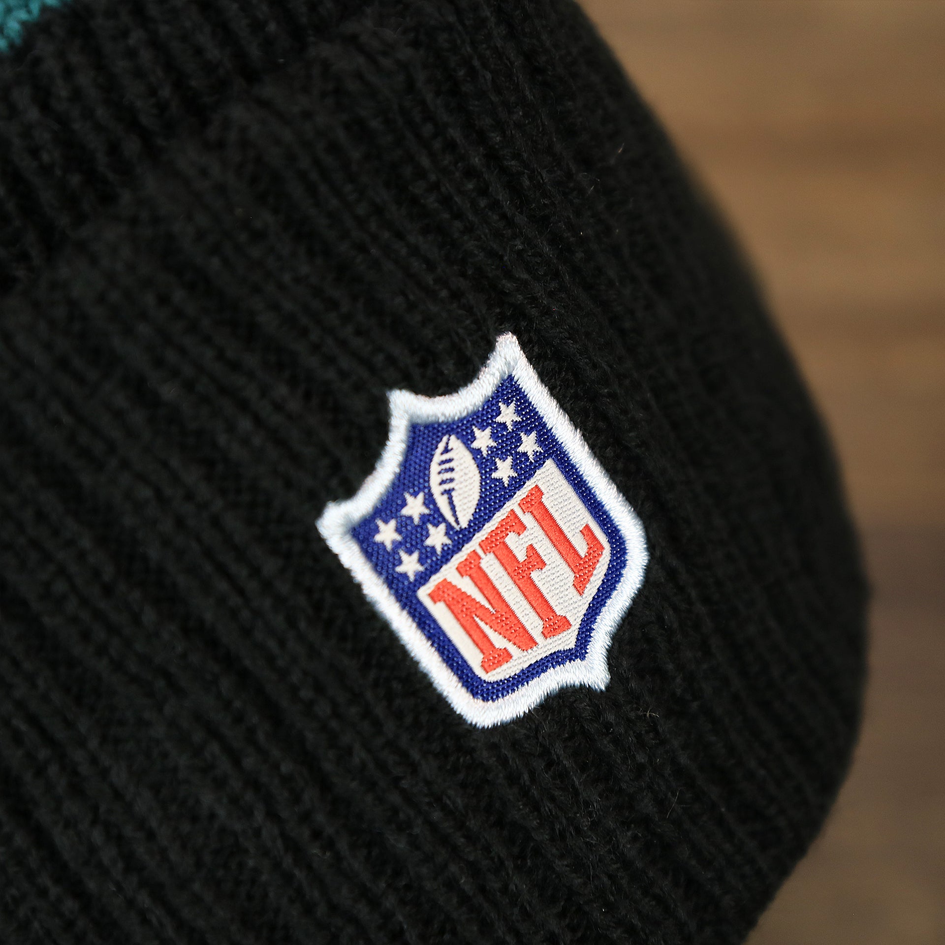 The NFL Logo on the Philadelphia Eagles Sideline On Field Pom Pom Winter Beanie | Black Winter Beanie
