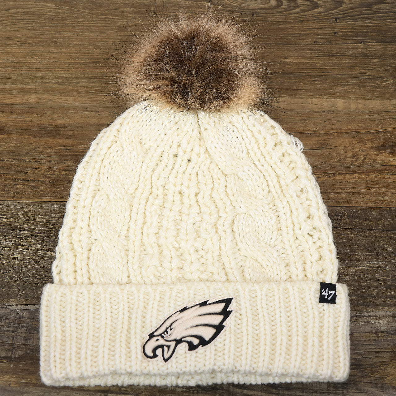 The front of the Women’s Philadelphia Eagles Cuffed Winter Knit Beanie With Meeko Pom Pom | Women’s Cream Winter Beanie
