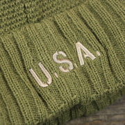The USA Wordmark on the Women’s Dallas Cowboys Salute To Service Ribbon Rubber Military Cowboys Patch On Field NFL Beanie | Women’s Military Green Beanie