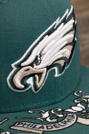 the logo on the front of the Philadelphia Eagles NFL Draft 2019 Snapback Hat | Philly Eagles Midnight Green 9Fifty Snapback Draft Hat is made of metallic raised embroidery