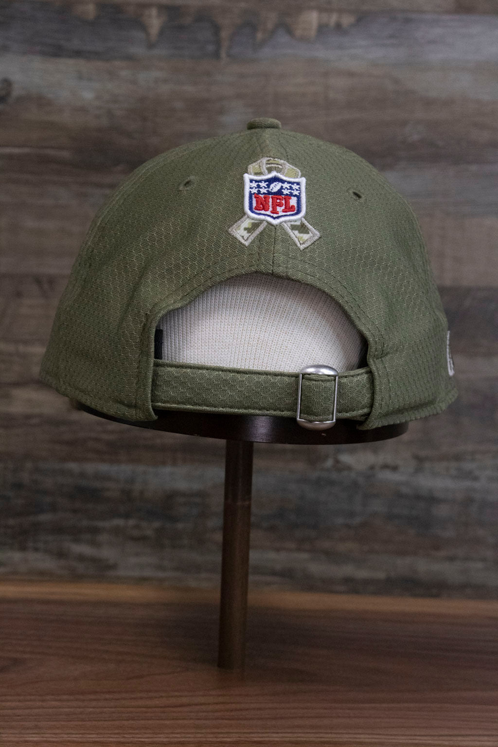 the back of the Pittsburgh Steelers 2019 Salute To Service Dad Hat | Steelers On Field Olive Green Military Inspired Baseball Cap has a large NFL shield and ribbon, plus an adjustable strap