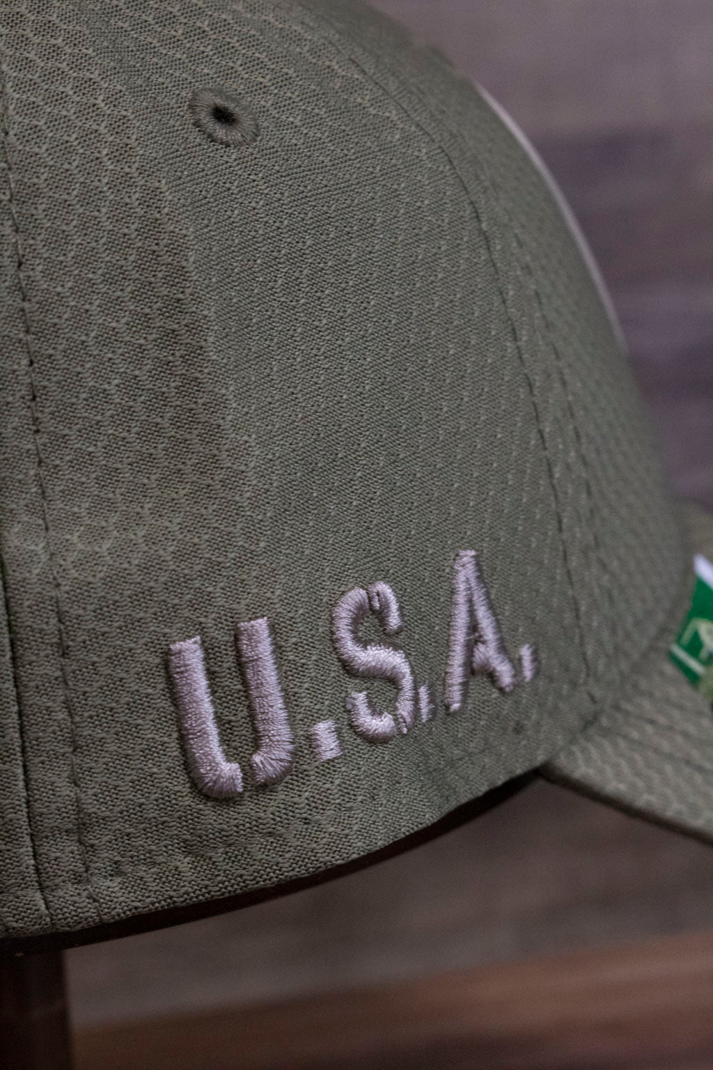 the side of the Pittsburgh Steelers 2019 Salute To Service Dad Hat | Steelers On Field Olive Green Military Inspired Baseball Cap has USA written on it