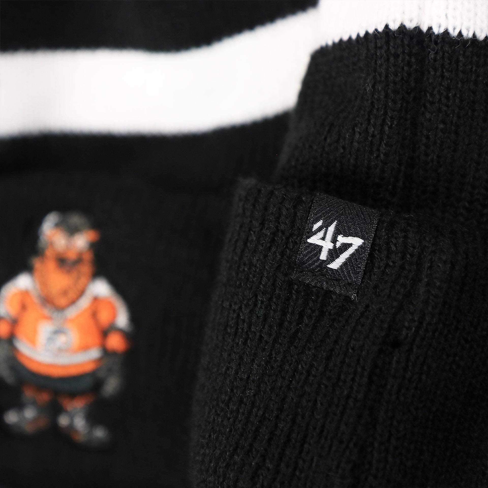 The 47 Brand Tag on the Philadelphia Flyers Mascot Gritty Black And White Striped Cuffed Pom Pom Winter Beanie | Black Winter Beanie