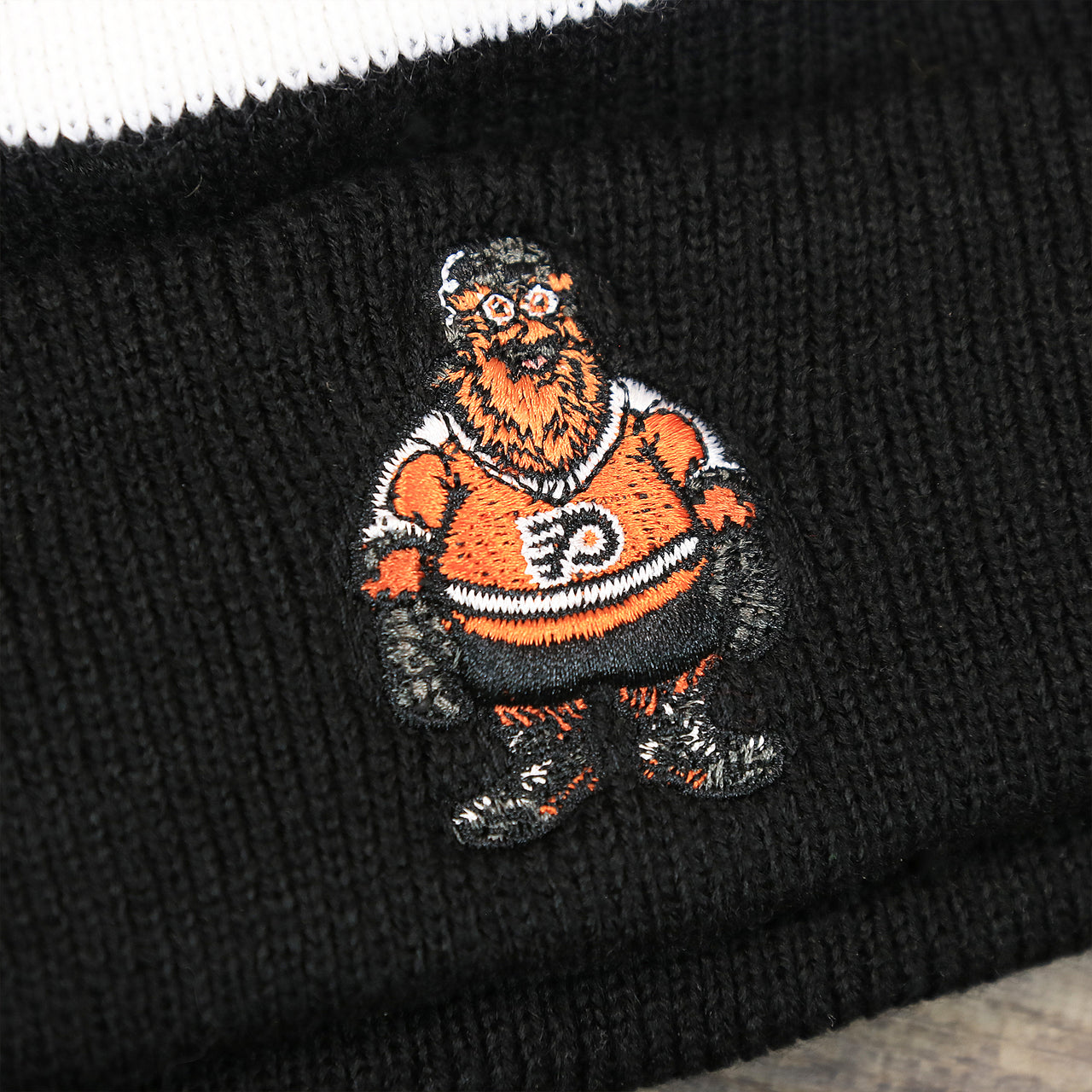 The Gritty Logo on the Philadelphia Flyers Mascot Gritty Black And White Striped Cuffed Pom Pom Winter Beanie | Black Winter Beanie
