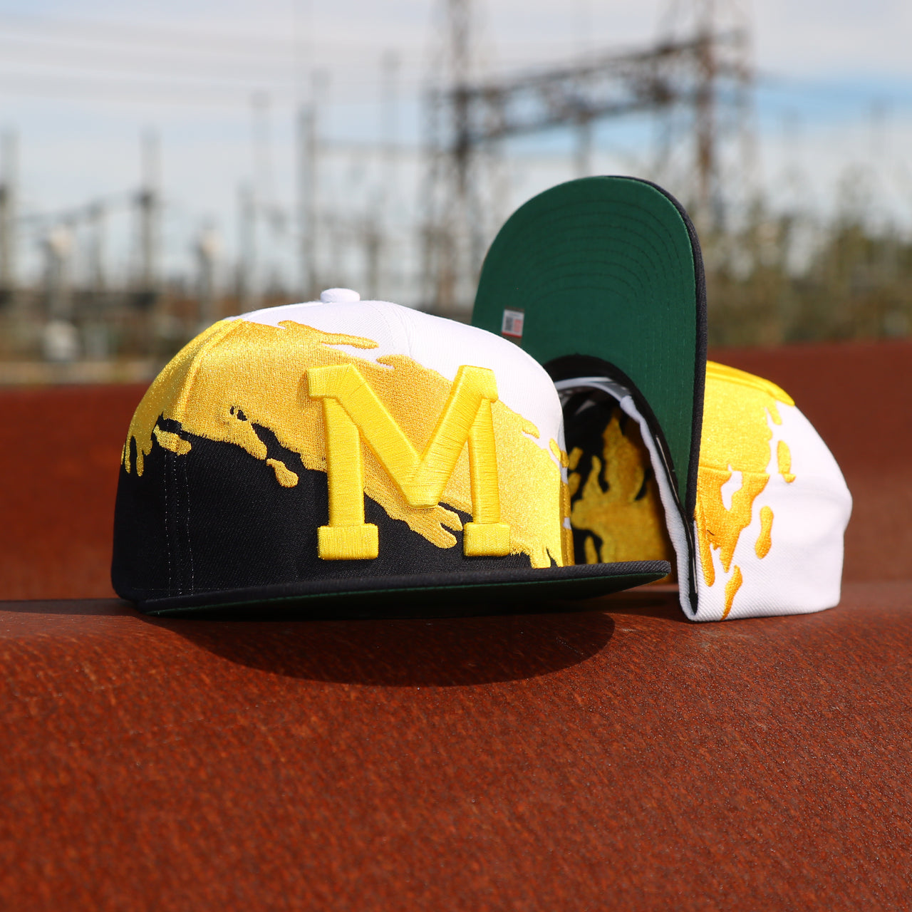 front and bottom of the University of Michigan Vintage Retro NCAA Paintbrush Mitchell and Ness Snapback Hat | Yellow/Navy Blue/White