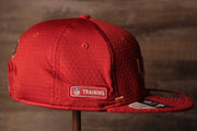 The wearers right side has the training camp logo 49ers 2020 Training Camp Snapback Hat | San Francisco 2020 On-Field Red Training Camp Snap Cap