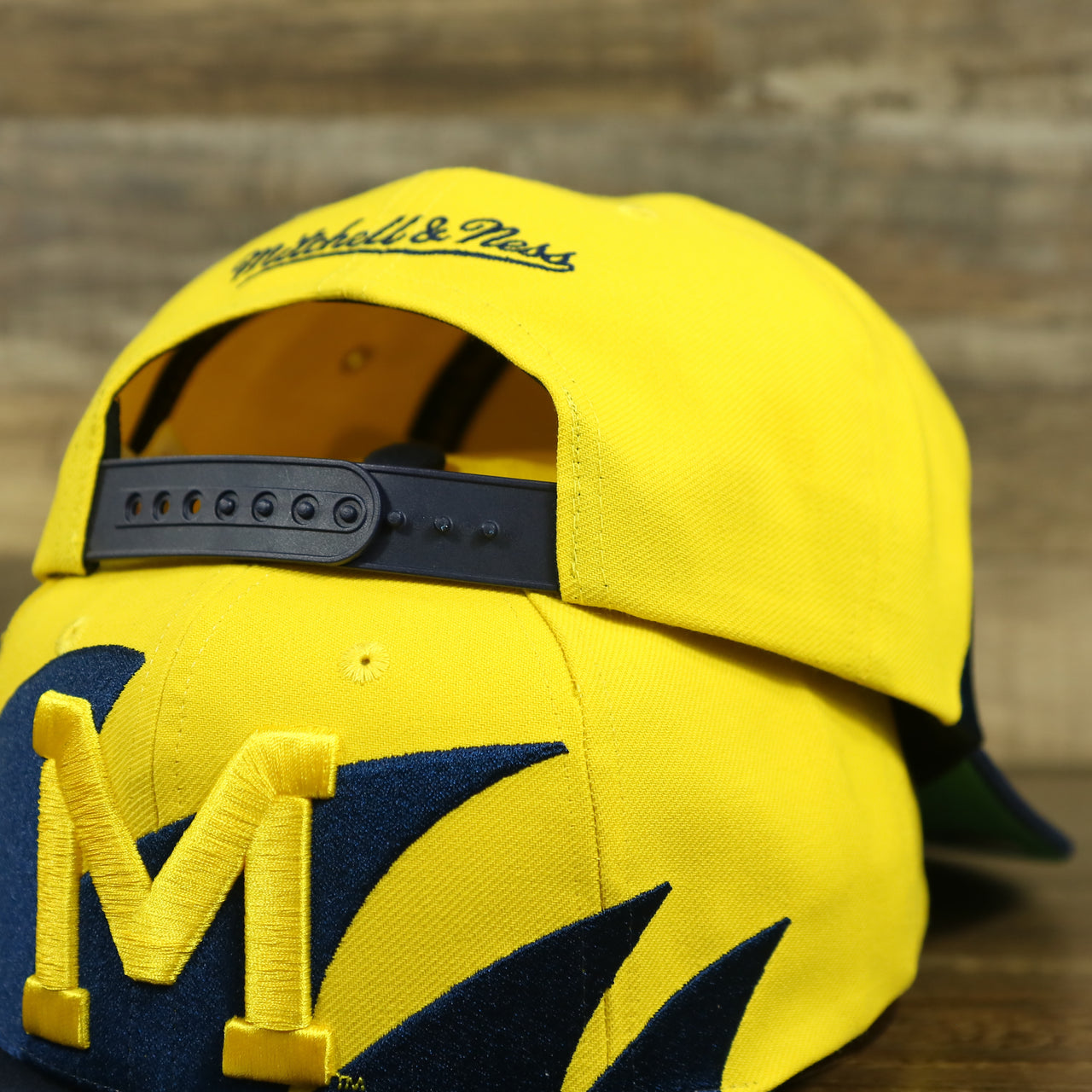 front and back of the University of Michigan Vintage Retro NCAA Sharktooth Mitchell and Ness Snapback Hat | Yellow/Navy Blue
