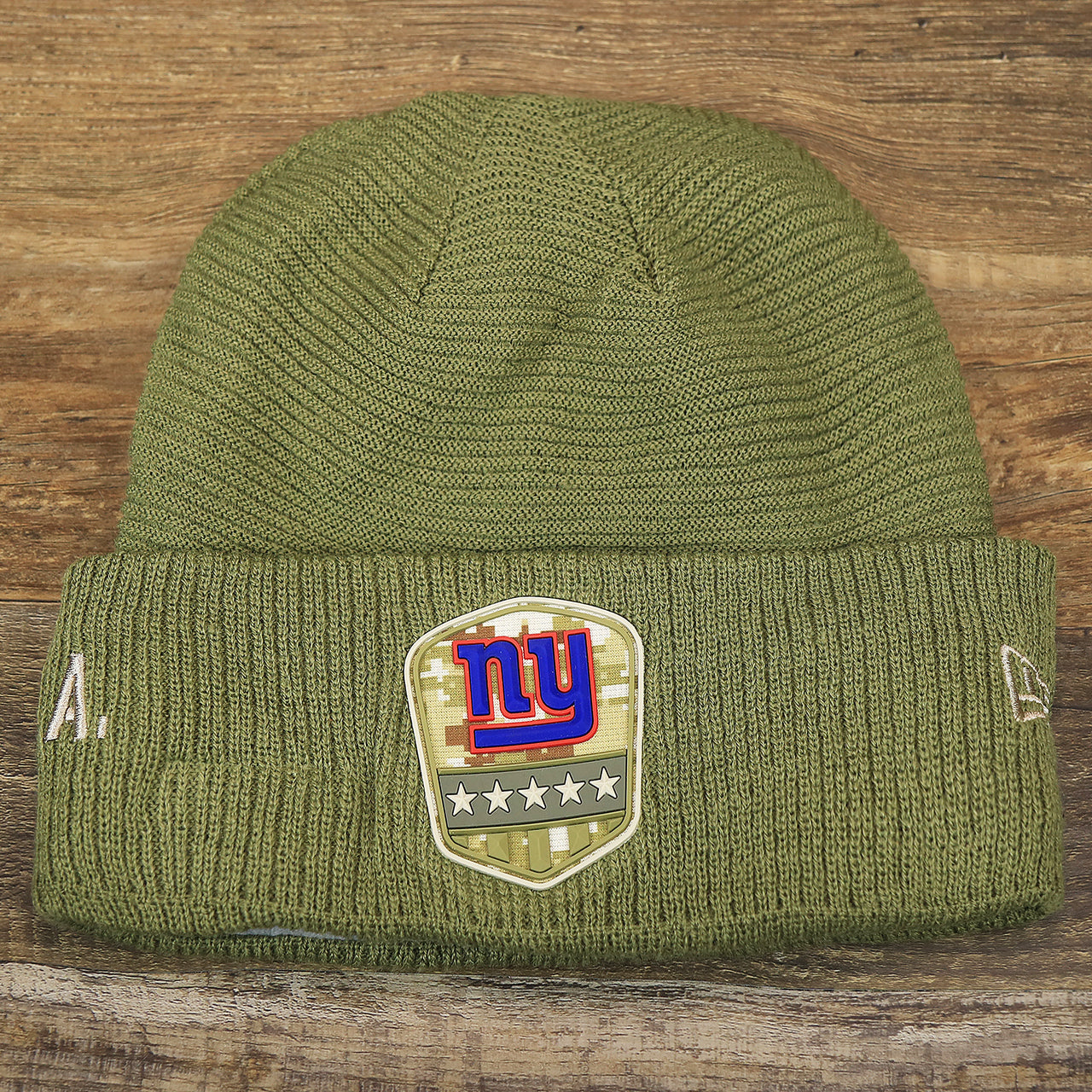 The front of the New York Giants Salute To Service Ribbon Rubber Military Giants Patch On Field NFL Beanie | Military Green Beanie