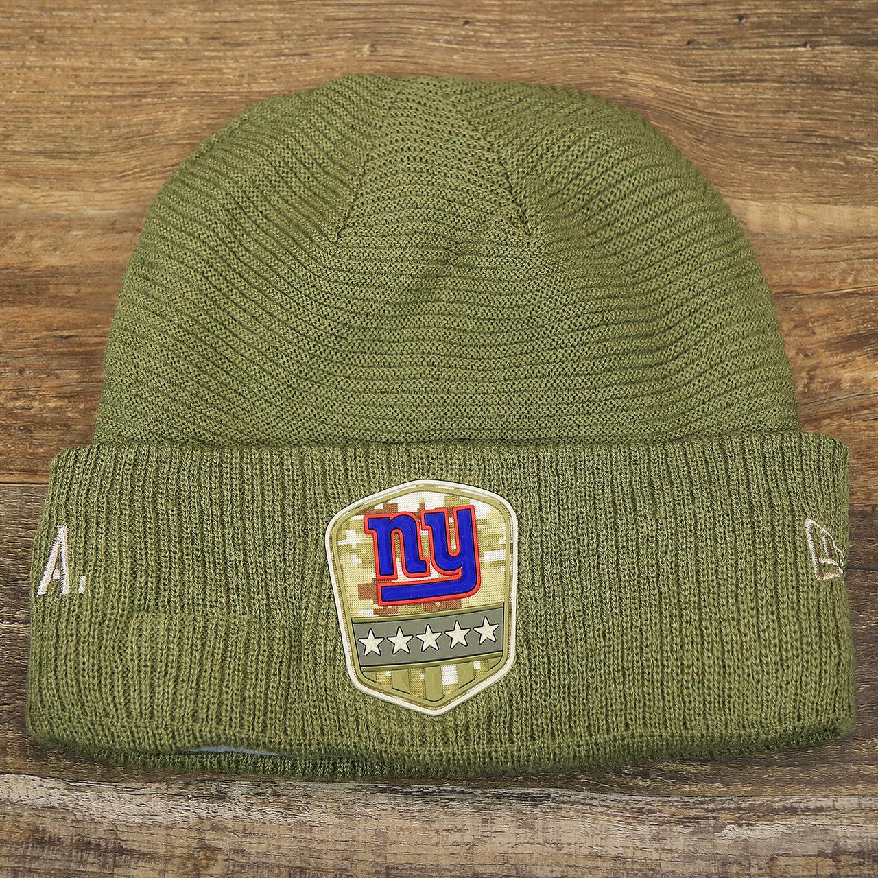 The front of the New York Giants Salute To Service Ribbon Rubber Military Giants Patch On Field NFL Beanie | Military Green Beanie