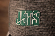 The jets logo is green with an outline of white Jets 2020 Training Camp Flexfit | New York Jets 2020 On-Field Grey Training Camp Stretch Fit