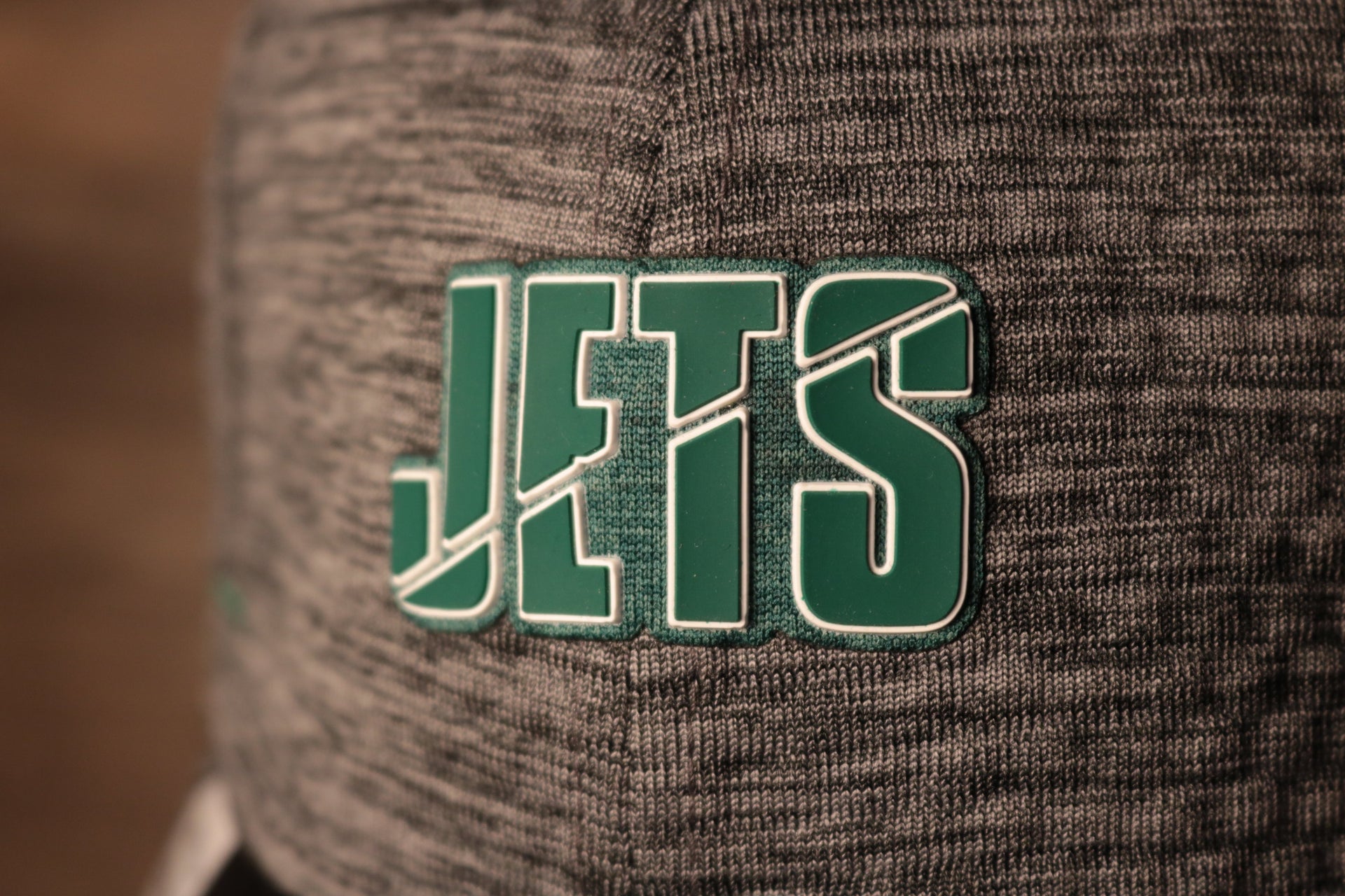 The jets logo is green with an outline of white Jets 2020 Training Camp Flexfit | New York Jets 2020 On-Field Grey Training Camp Stretch Fit