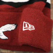 The New Era Logo on the Throwback Philadelphia Eagles White Logo Striped Cuffed Winter Beanie | Maroon Winter Beanie