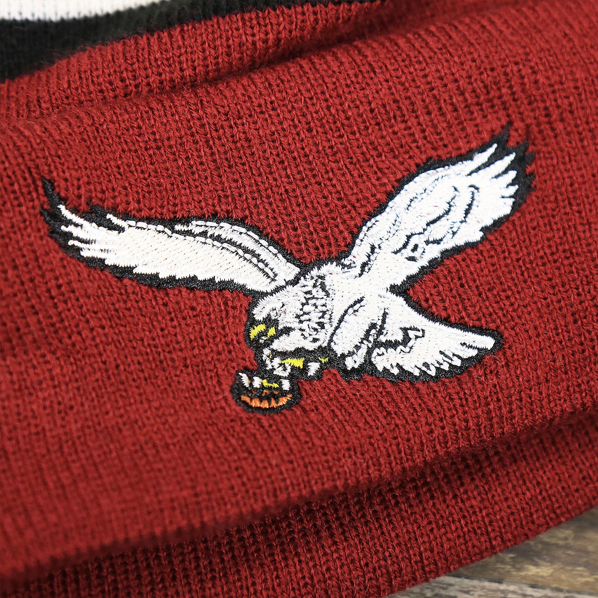 The Throwback White Eagles Logo on the Throwback Philadelphia Eagles White Logo Striped Cuffed Winter Beanie | Maroon Winter Beanie