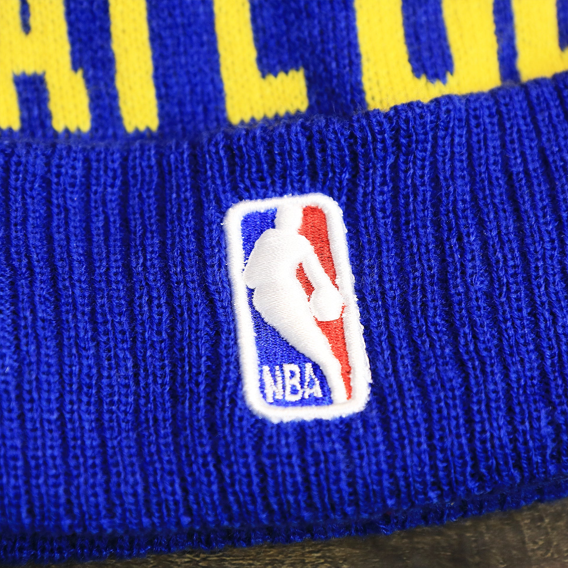 The NBA Jerrywest Logo on the Golden State Warriors Wrapped Around Wordmark Pom Pom Winter Beanie | Blue Winter Beanie
