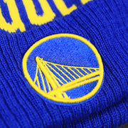 The Golden State Warriors Logo on the Golden State Warriors Wrapped Around Wordmark Pom Pom Winter Beanie | Blue Winter Beanie