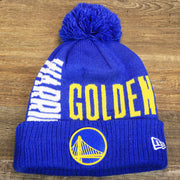 The front of the Golden State Warriors Wrapped Around Wordmark Pom Pom Winter Beanie | Blue Winter Beanie
