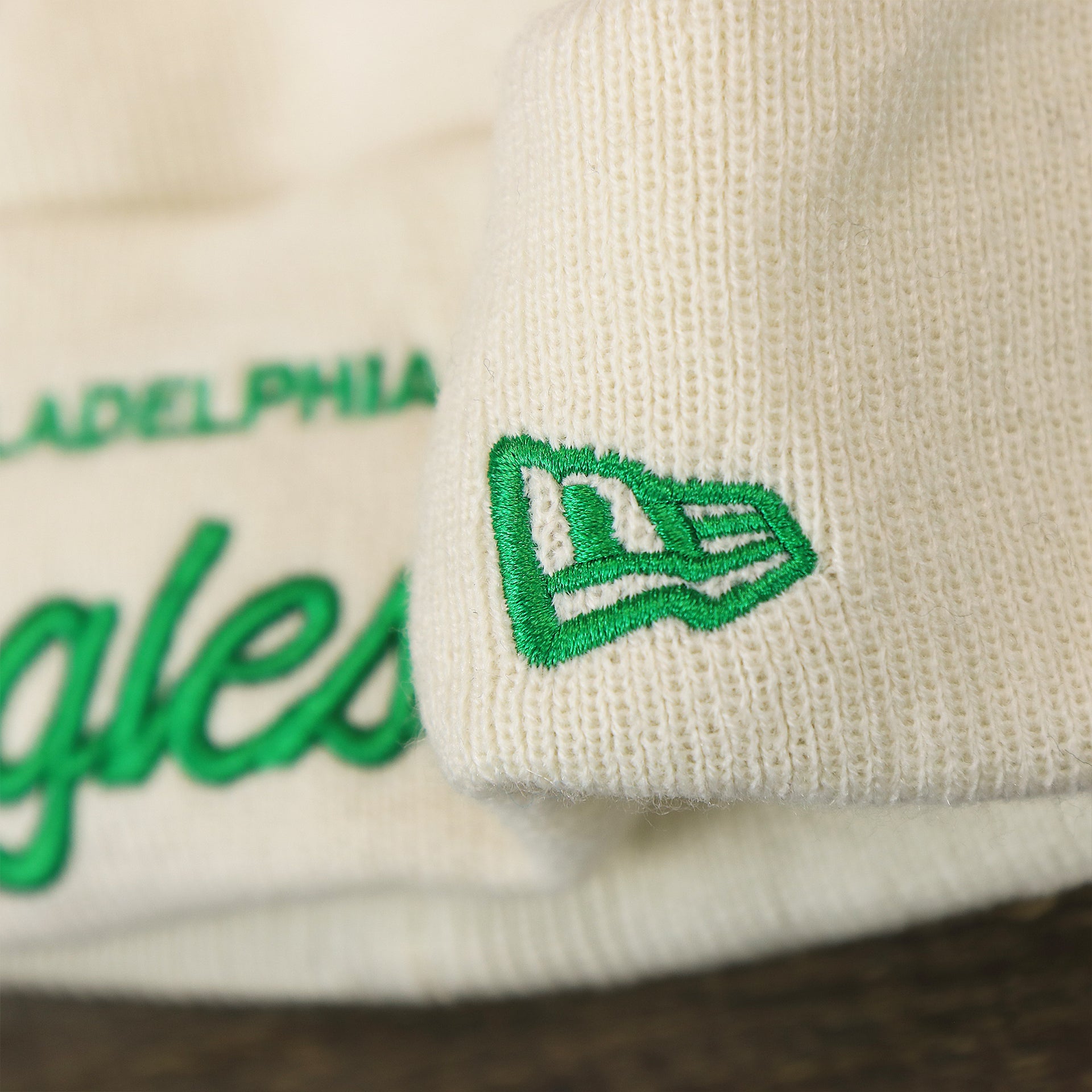 The New Era Logo on the Philadelphia Eagles Script Cuffed Winter Beanie With Pom Pom | Ivory Winter Beanie