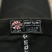 The Foot Clan Tag on the Jet Black Structured Cotton Blank Small Fit Flexfit Cap | Black Stretch Fit Caps
