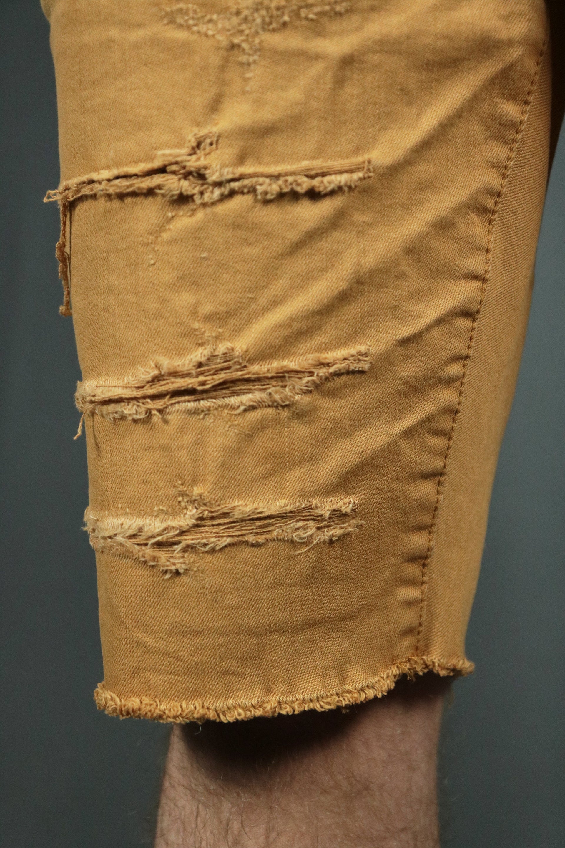Khaki men distressed shorts with rips by Jordan Craig.