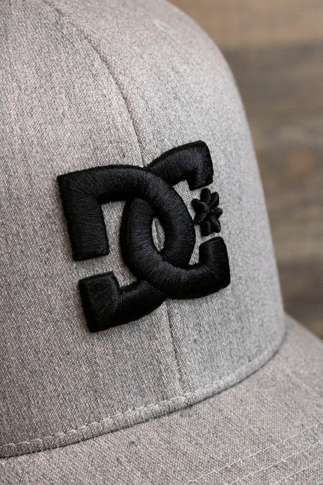 the DC logo on the Light Gray Bentbrim Skater Hat | DC Shoes Black Bottom Heather Gray Flexfit Cap is made of black puff embroidery
