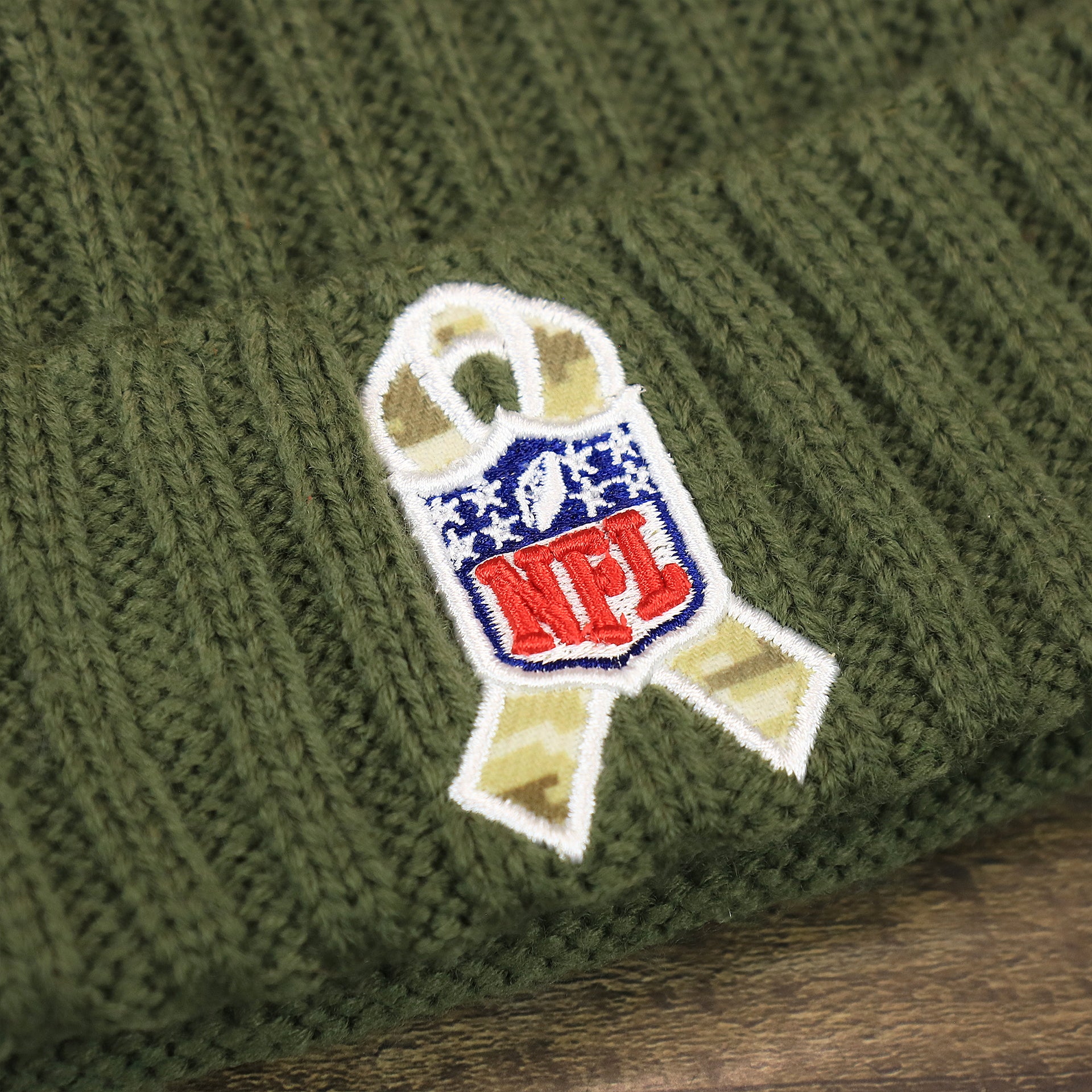 The NFL Salute To Service Ribbon on the Youth Dallas Cowboys on Field Salute To Service Ribbon American Flag Side Patch Winter Beanie | Kid’s Olive Green Winter Beanie