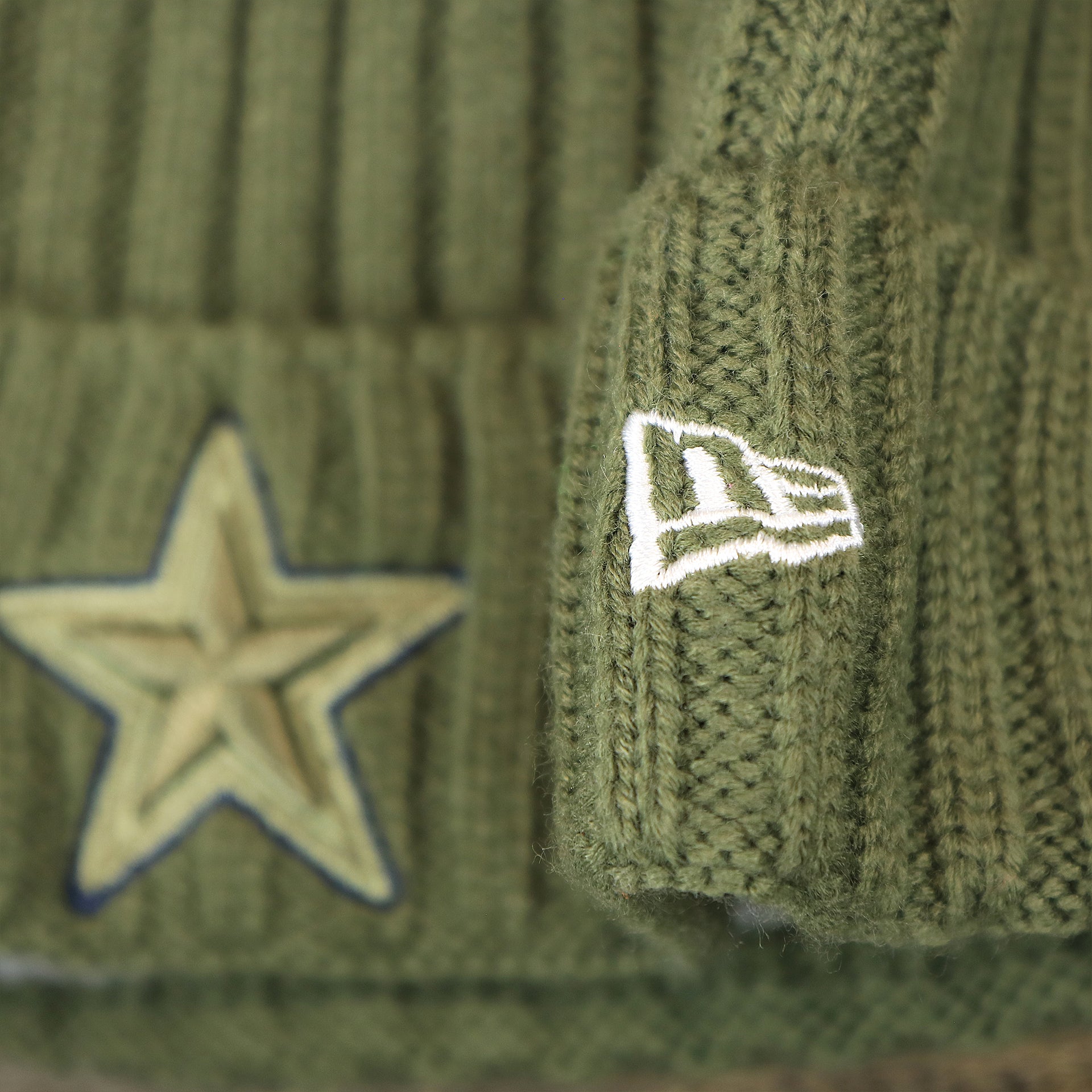 The New Era Logo on the Youth Dallas Cowboys on Field Salute To Service Ribbon American Flag Side Patch Winter Beanie | Kid’s Olive Green Winter Beanie