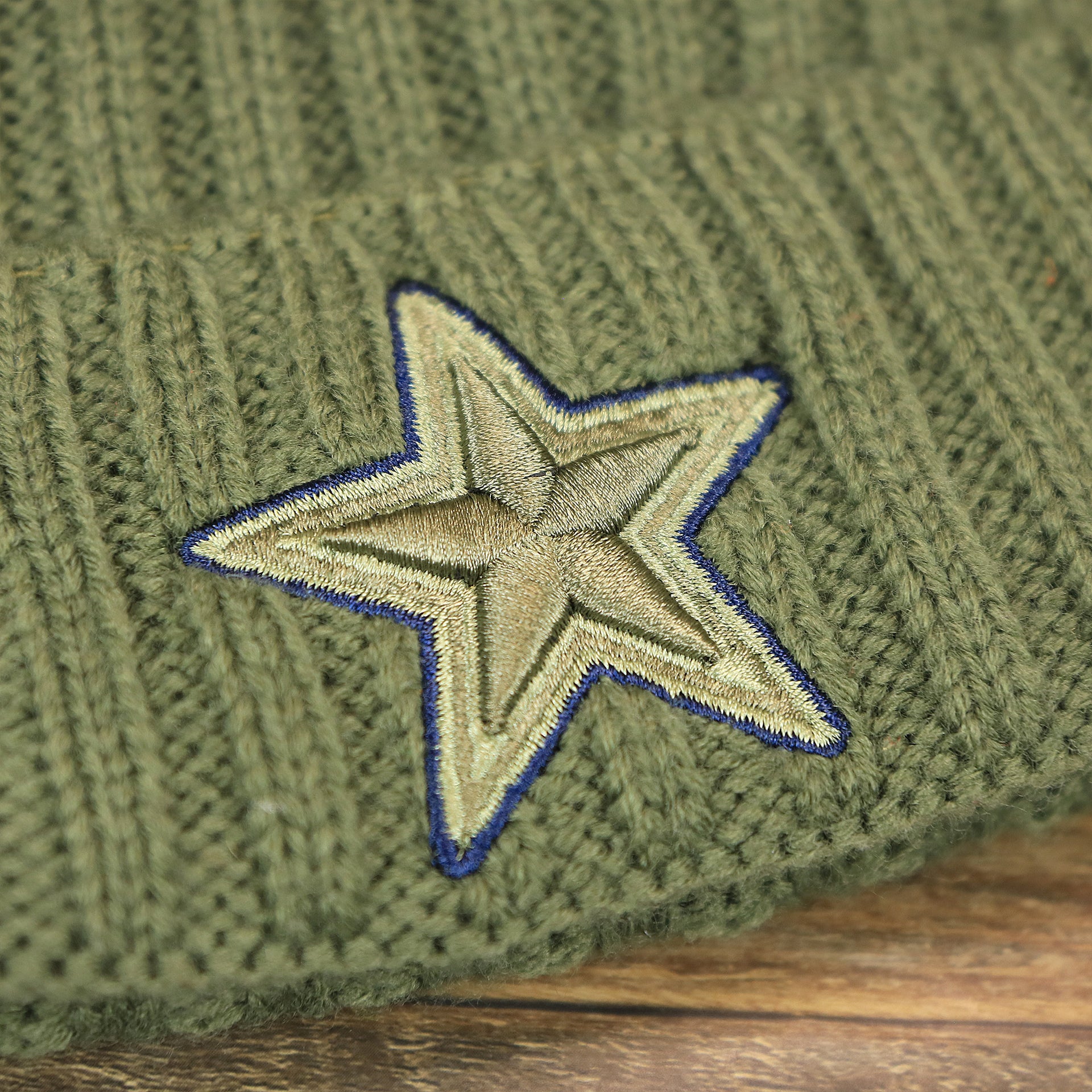 The Cowboys Logo on the Youth Dallas Cowboys on Field Salute To Service Ribbon American Flag Side Patch Winter Beanie | Kid’s Olive Green Winter Beanie