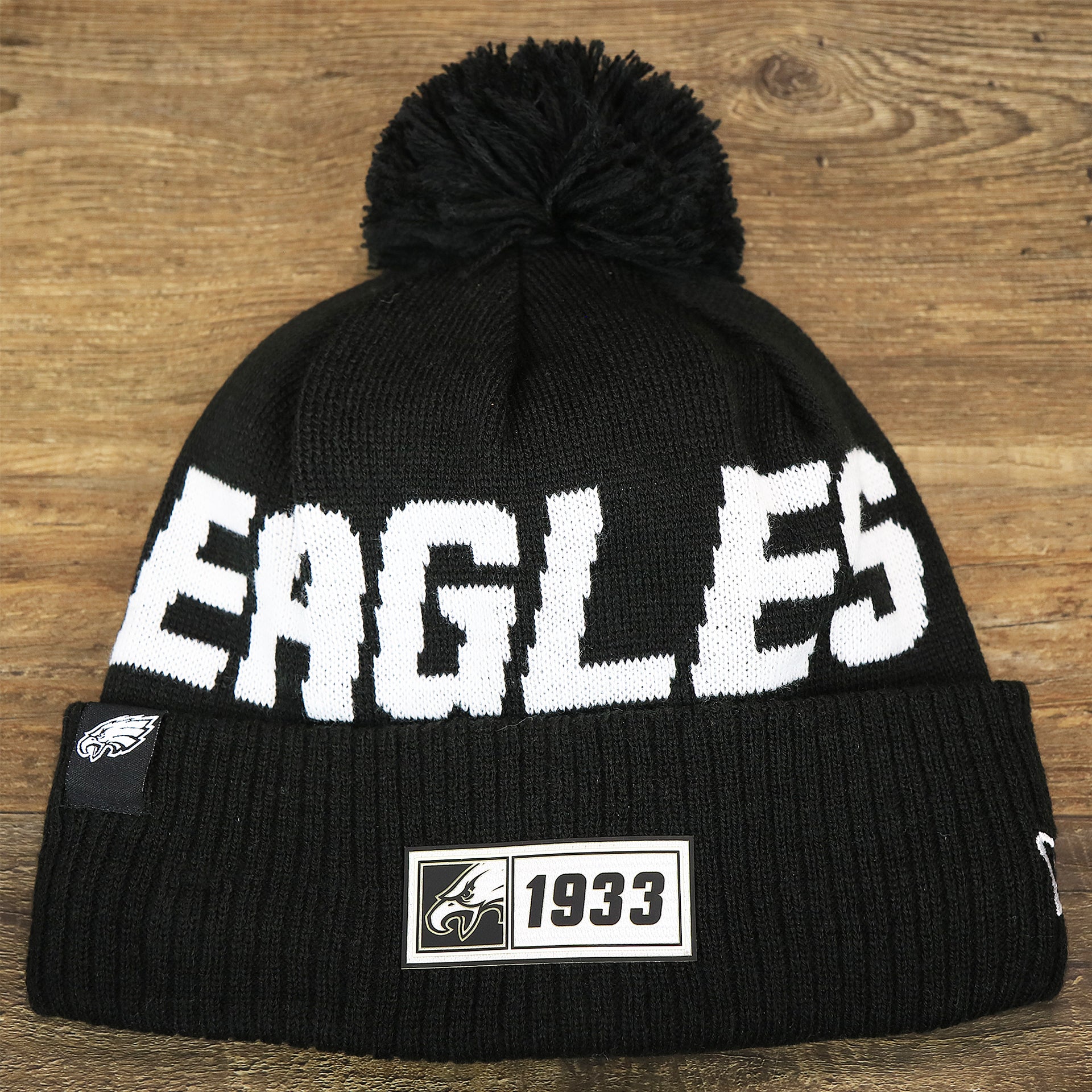 The front of the Philadelphia Eagles On Field Cuffed Winter Pom Pom Beanie | Black And White Winter Beanie