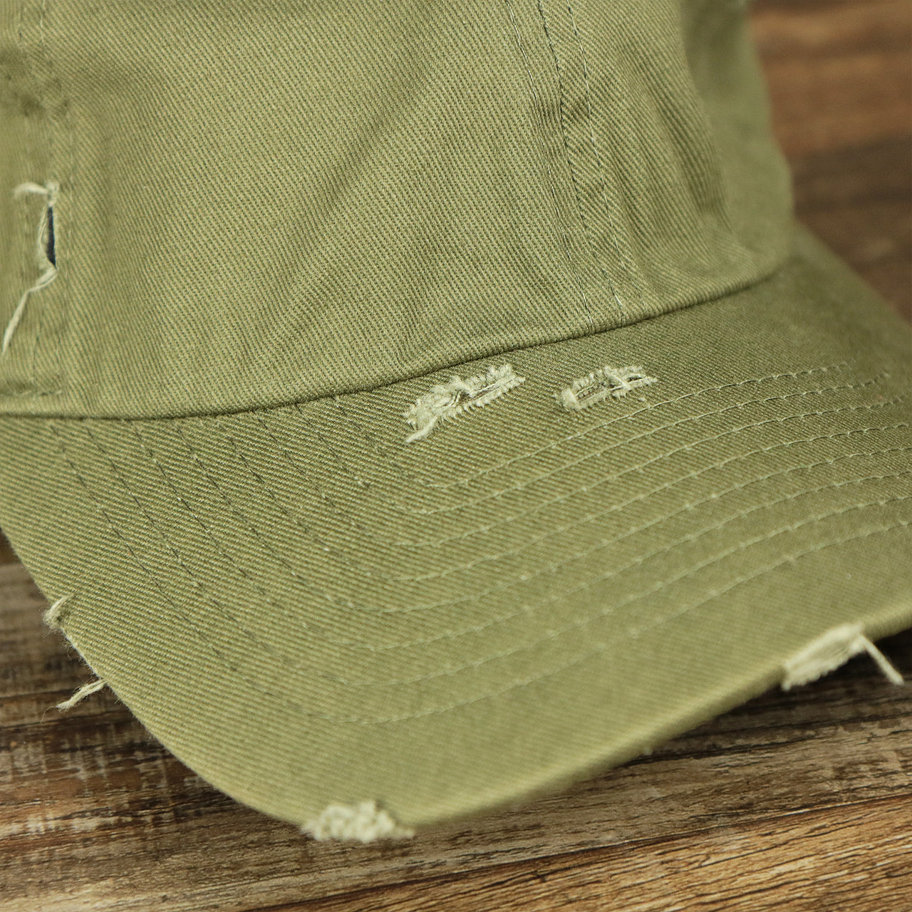 The visor on the Olive Green Low Crown Distressed Adjustable Blank Baseball hat | Dark Green Dad Hat