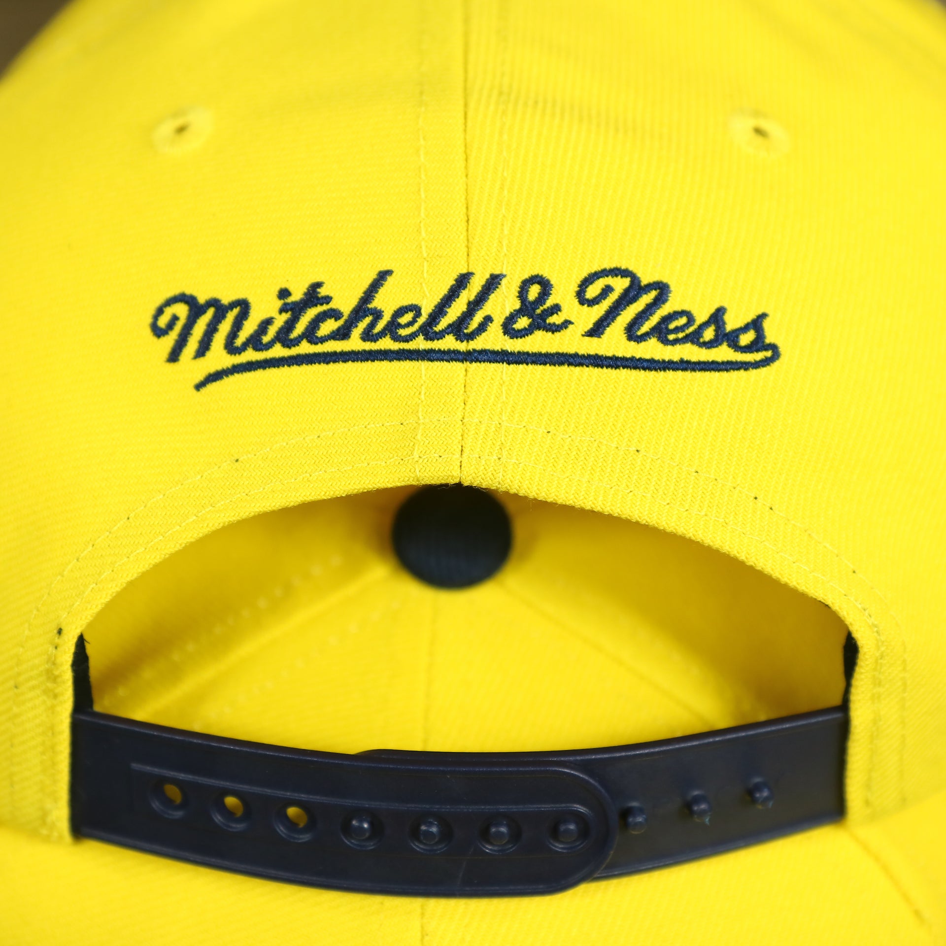 mitchell and ness logo on the University of Michigan Vintage Retro NCAA Sharktooth Mitchell and Ness Snapback Hat | Yellow/Navy Blue