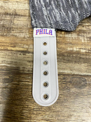 on the strap of the Philadelphia 76ers Flyknit Look Space Dye Gray Trucker Dad Hat is a Phila team logo tag