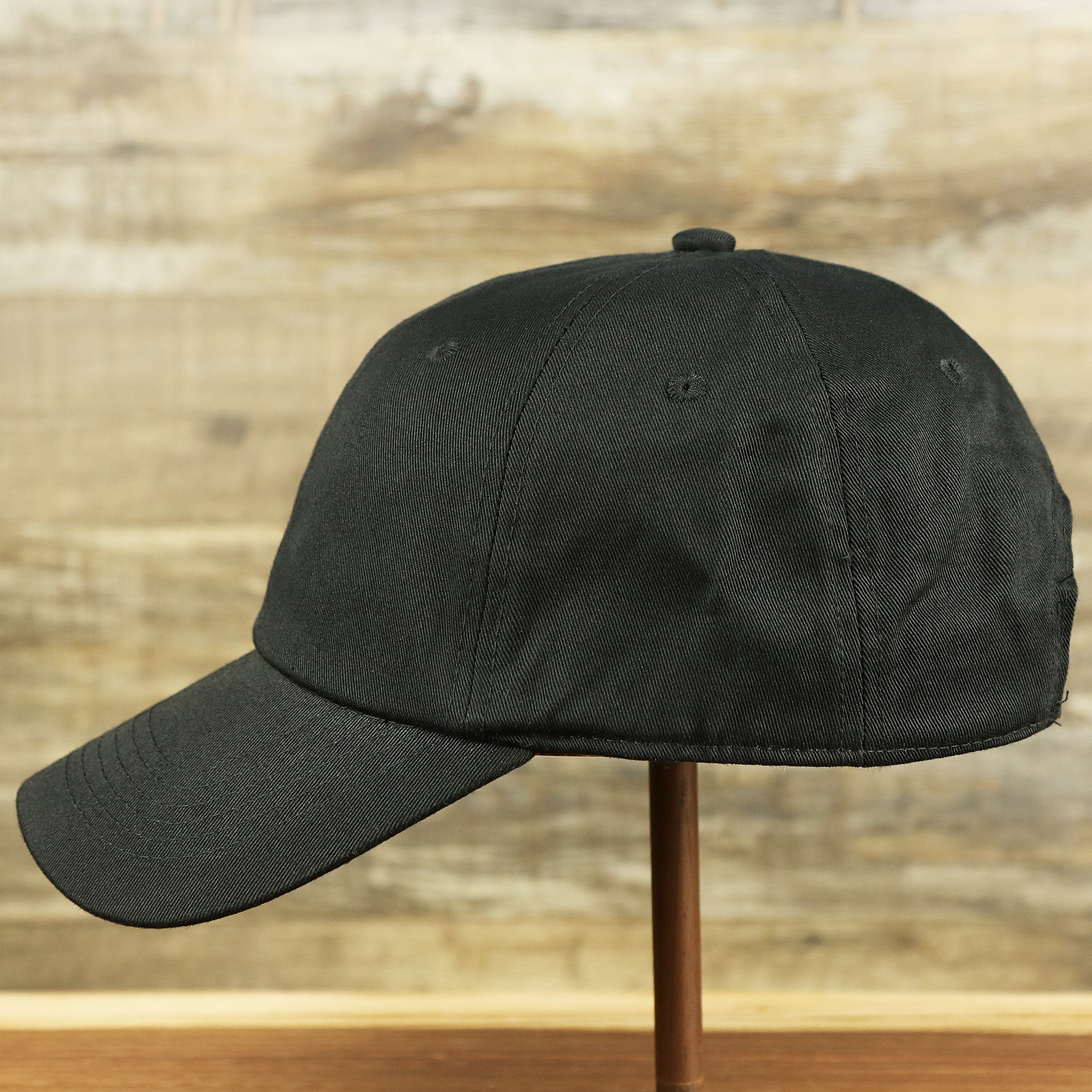 The wearer's left of the Jet Black Blank Baseball Hat | Black Dad Hat