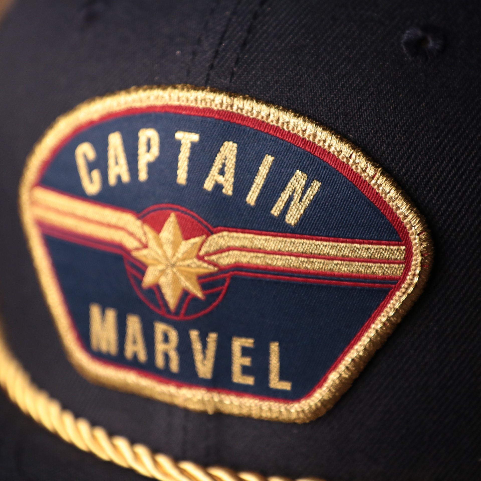 the captain marvel logo is gold, navy blue, and red Captain Marvel Red Bottom Snapback | Captain Marvel Navy Trucker Red Bottom Snap Cap