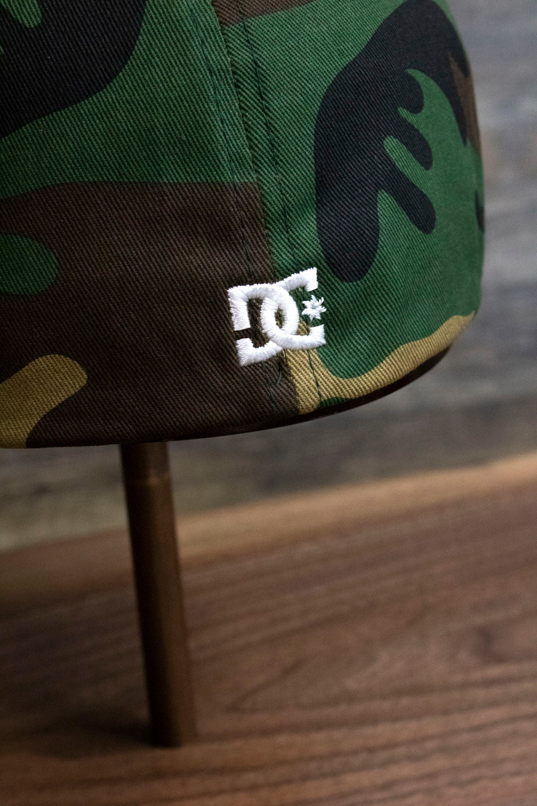 the Camouflage Print Skater Hat | DC Shoes Black Bottom Camo Flexfit Cap has a DC logo