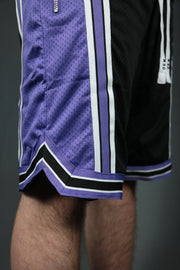 A model wearing the Sacramento black purple basketball shorts with zipper pockets by Jordan Craig.