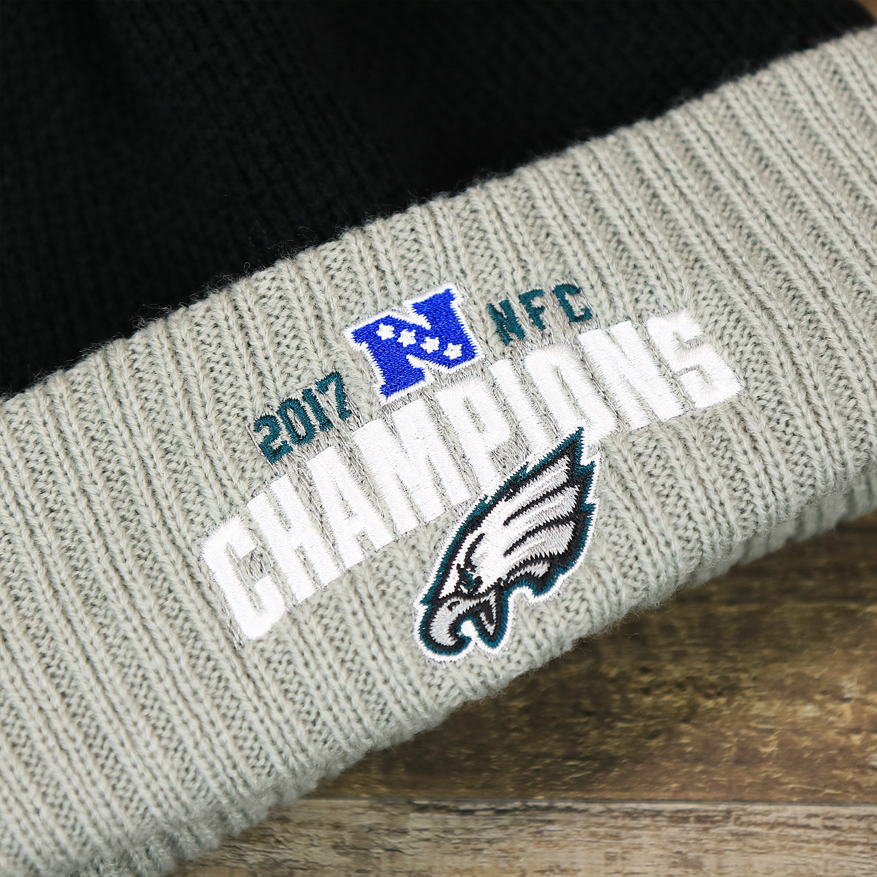 The 2017 NFC Eagles Champions Logo on the Philadelphia Eagles 2017 NFC Champions Gray Cuff NFL Pom Pom Winter Beanie | Black Winter Beanie