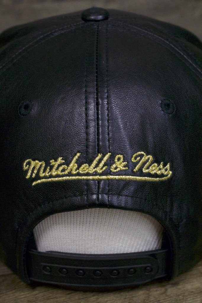 the mitchell ness logo is also gold on the Golden State Warriors Leather Snapback | Black Warriors Snap Back with Gold Foil Design
