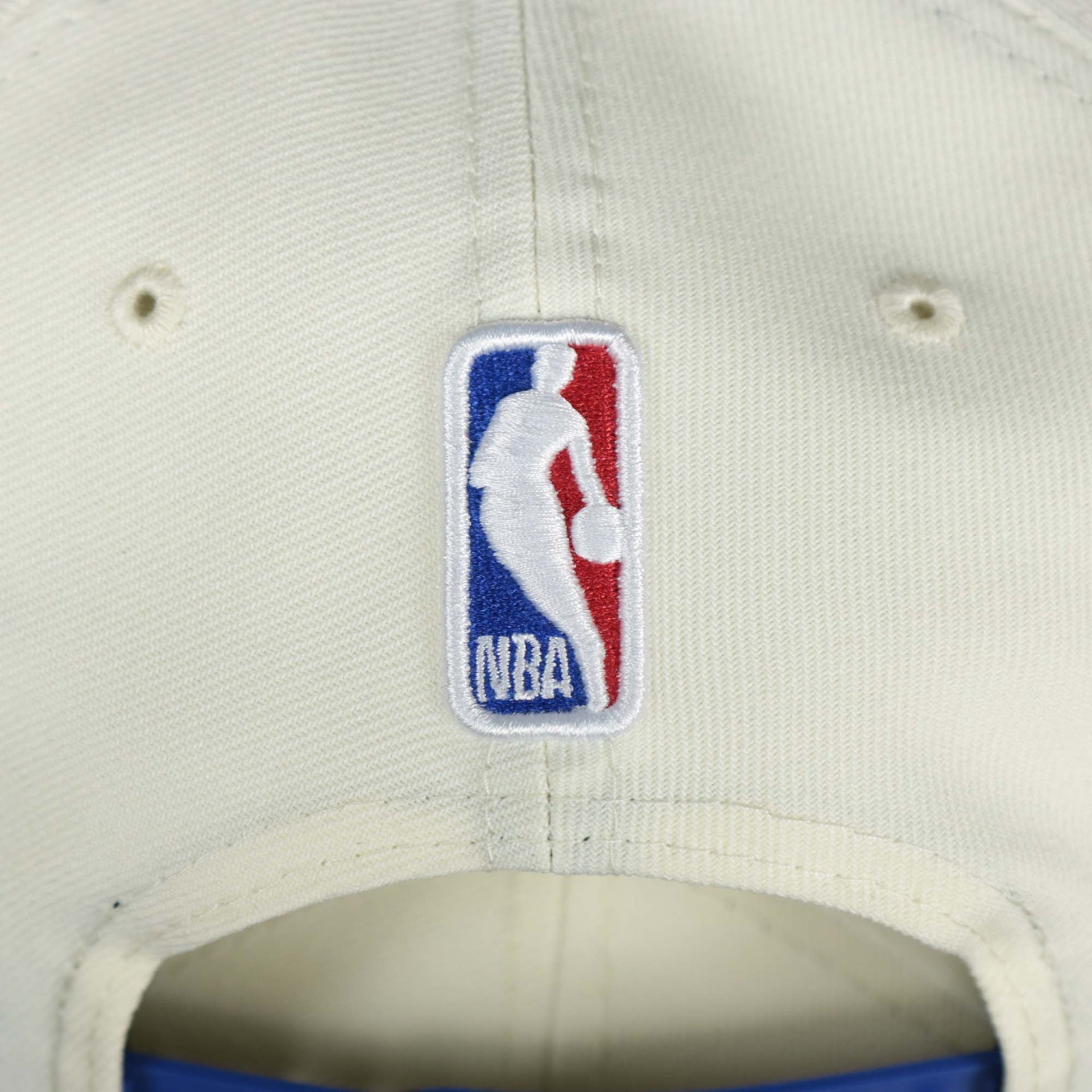 The NBA Jerry West Logo on the back of the Philadelphia 76ers NBA 2022 Draft Gray Bottom 9Fifty Snapback | New Era Cream/Royal Blue