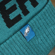 The Eagles Tag on the Philadelphia Eagles On Field Since 1933 Eagles Patch Winter Pom Pom Beanie | Midnight Green Winter Beanie