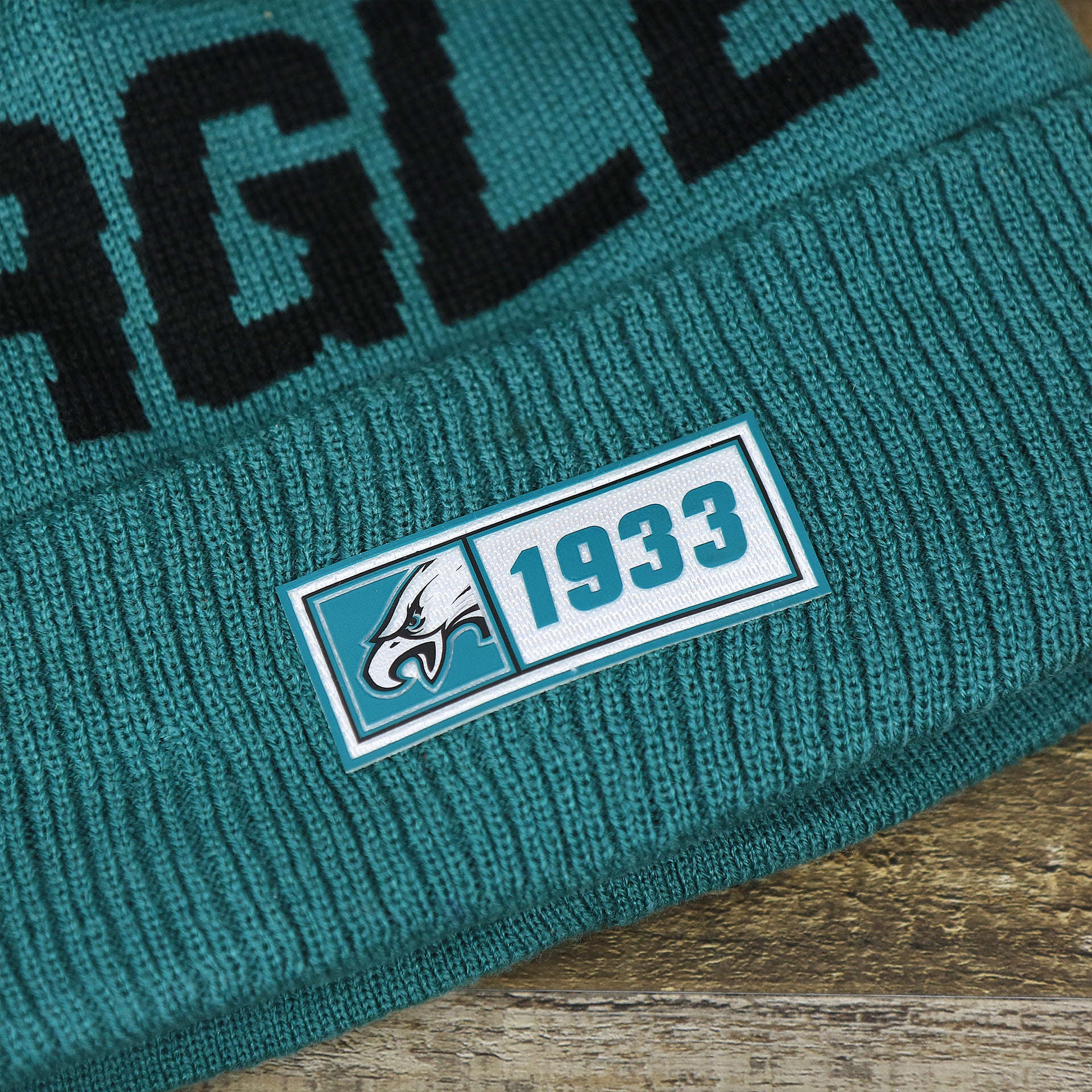 The 1933 Eagles Rubber Logo on the Philadelphia Eagles On Field Since 1933 Eagles Patch Winter Pom Pom Beanie | Midnight Green Winter Beanie