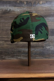 the back of the Camouflage Print Skater Hat | DC Shoes Black Bottom Camo Flexfit Cap has a tiny DC Shoes logo on it