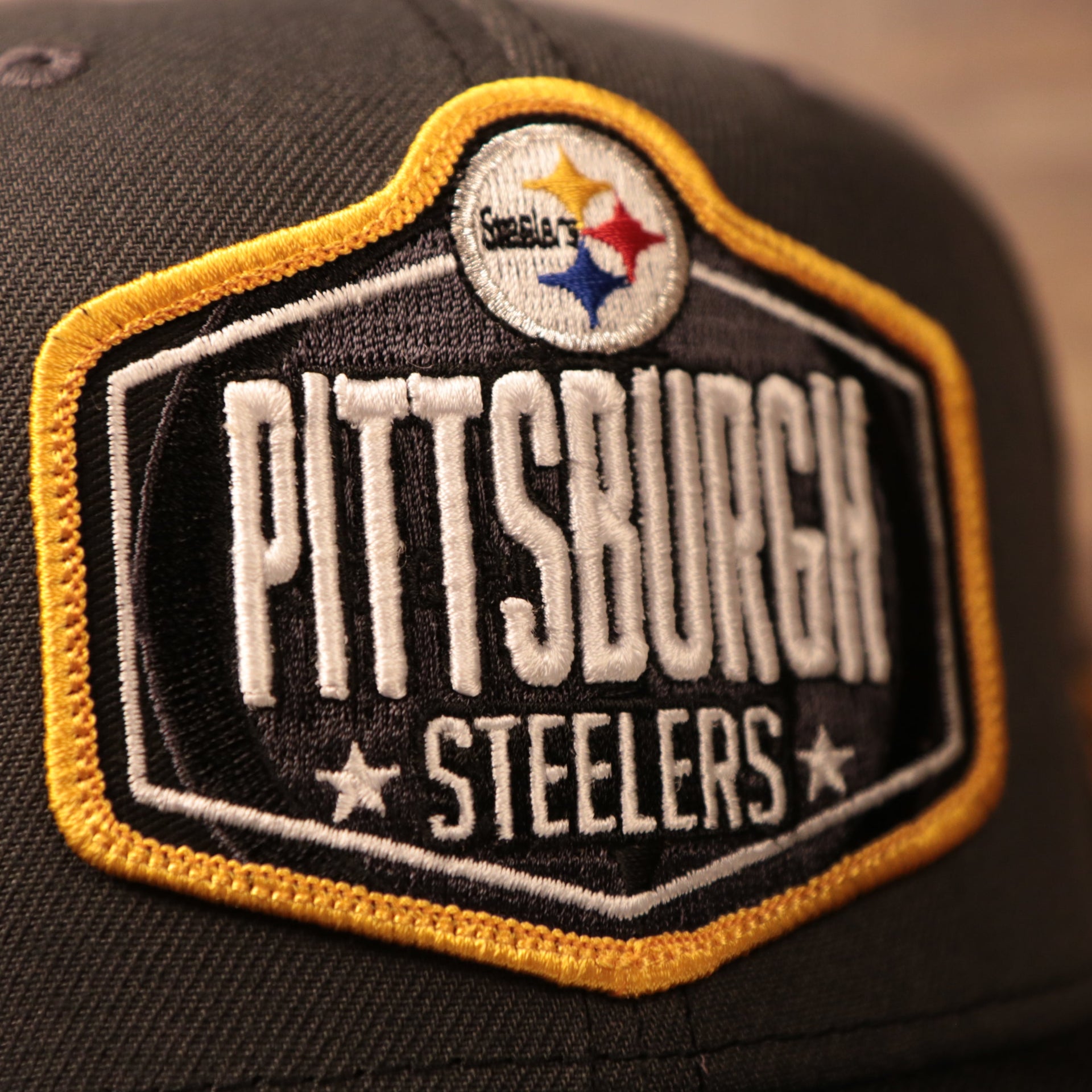 The Pittsburgh Steelers logo on the front of the gray/black meshback 2021 NFL draft trucker hat.