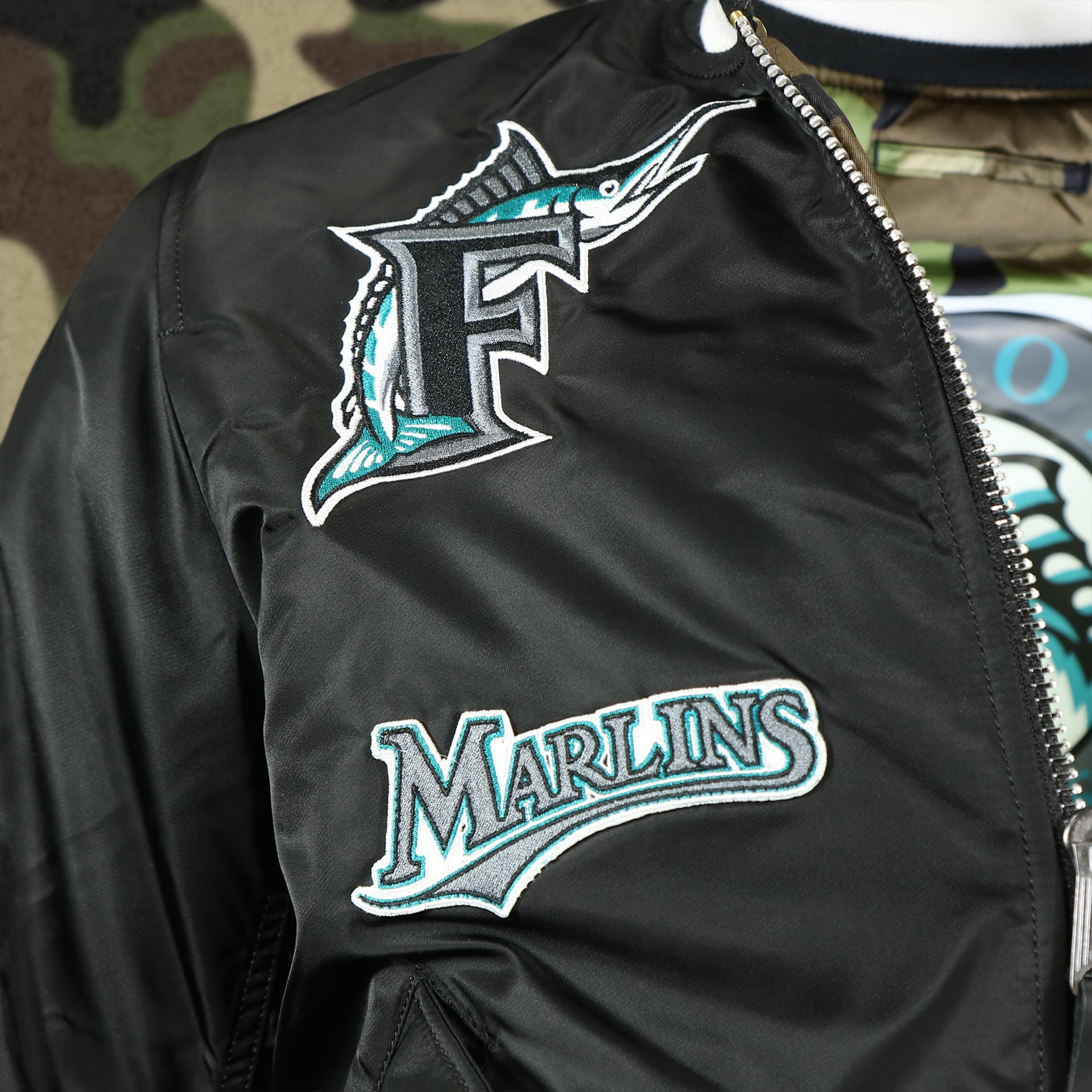 throwback marlins logo and wordmark on the Florida Marlins MLB Patch Alpha Industries Reversible Bomber Jacket With Camo Liner | Black Bomber Jacket